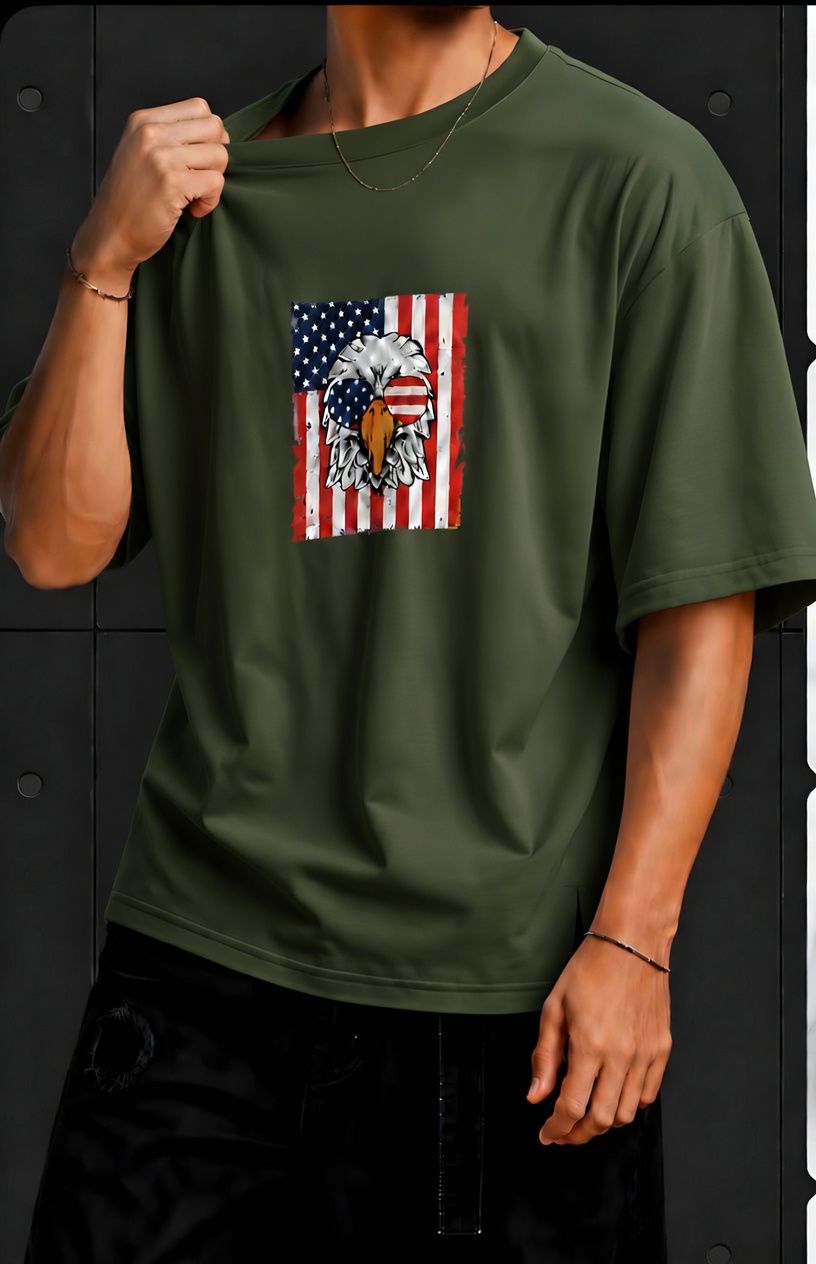 American Eagle Graphic Oversized T-Shirt – Olive Green Olive green oversized T-shirt featuring an American eagle and flag graphic on the front, paired with black pants.