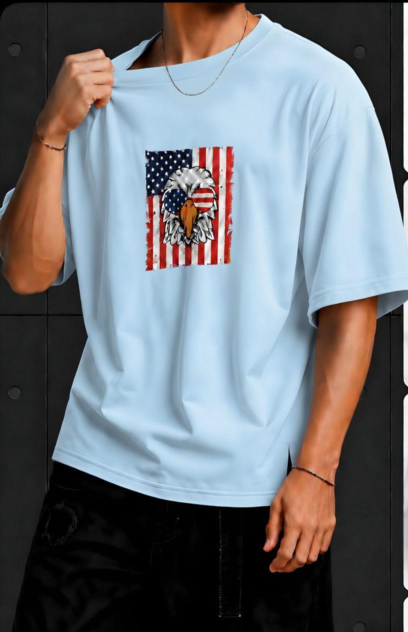 American Eagle Graphic Oversized T-Shirt – Light Blue Light blue oversized T-shirt featuring an American eagle and flag graphic on the front, worn with black pants.